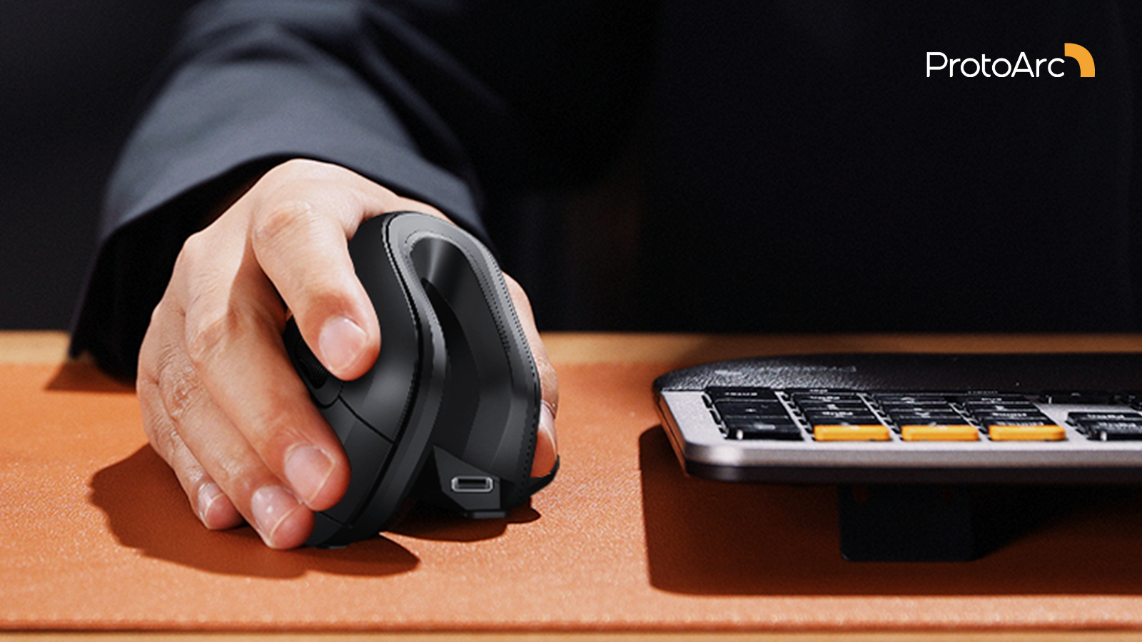 Hand using a sleek ergonomic mouse next to a keyboard.
