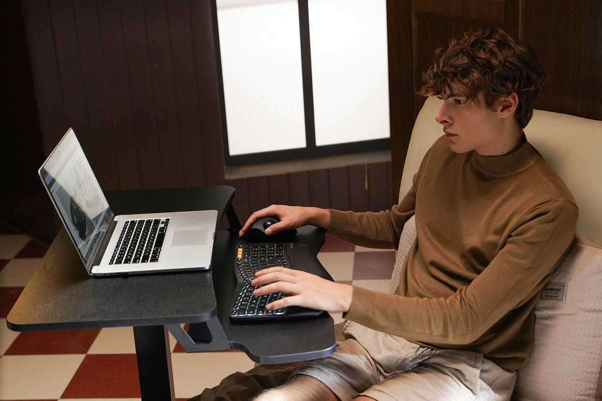 A person using a laptop with an ergonomic mouse.