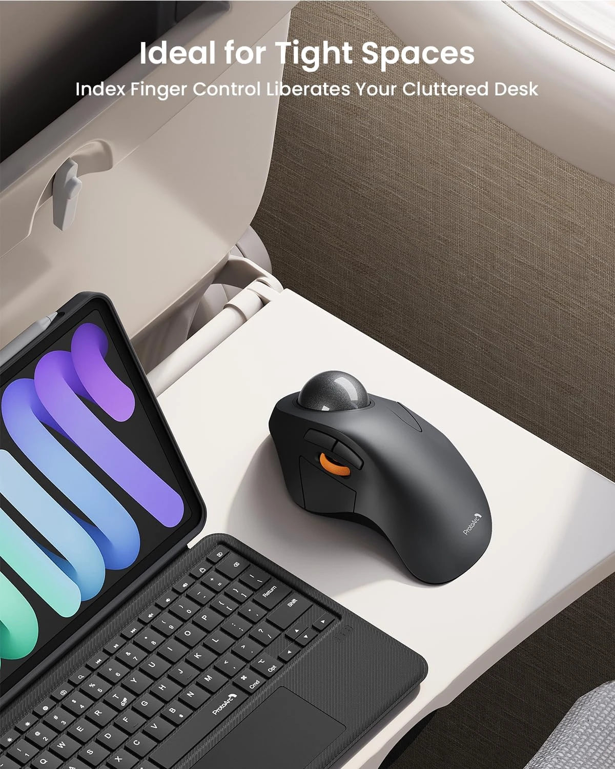 Black ergonomic trackball mouse with gray ball, next to a tablet and keyboard.