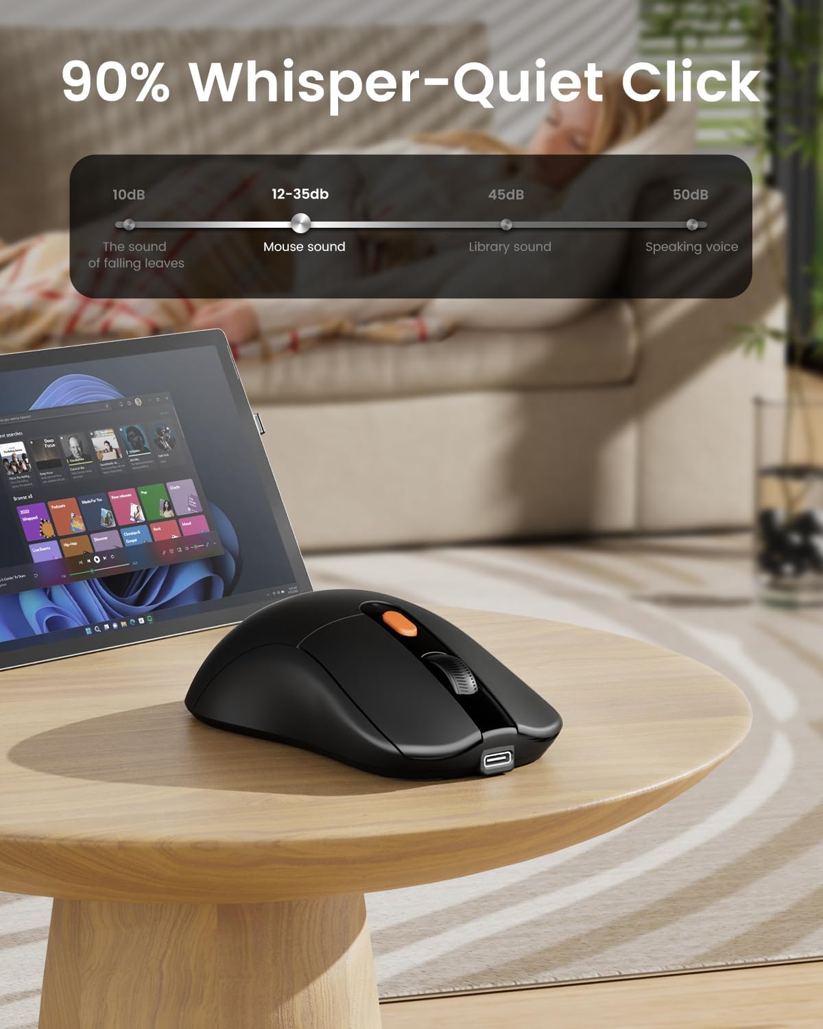 Black EM15 USB C mouse with orange accents on a table, showcasing its 90% whisper-quiet click feature.