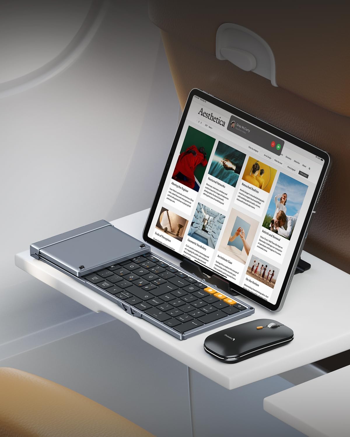 XKM01 Tri-Fold Bluetooth Keyboard DE layout folded next to ergonomic mouse with tablet, showcasing mobile workstation setup.